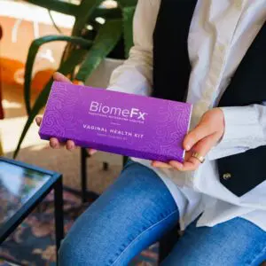 Person holding a purple BiomeFx box with green plants in the background.