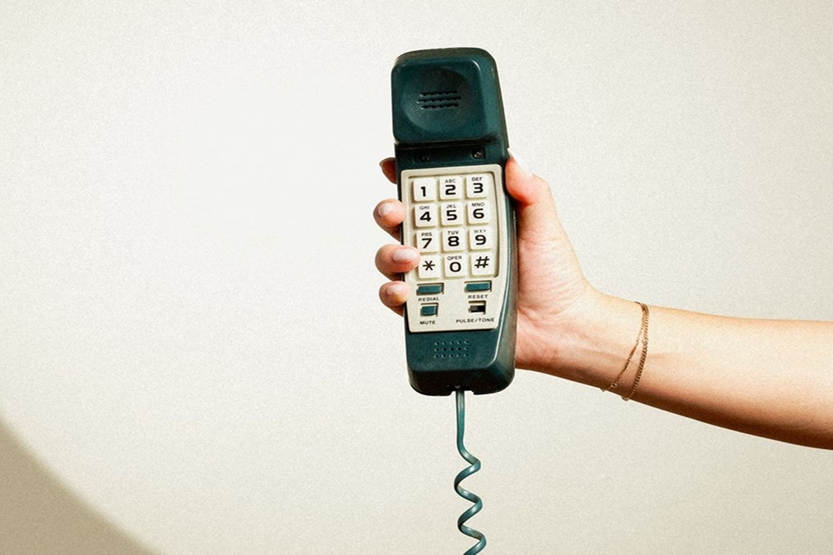 A hand holding a vintage corded telephone receiver.
