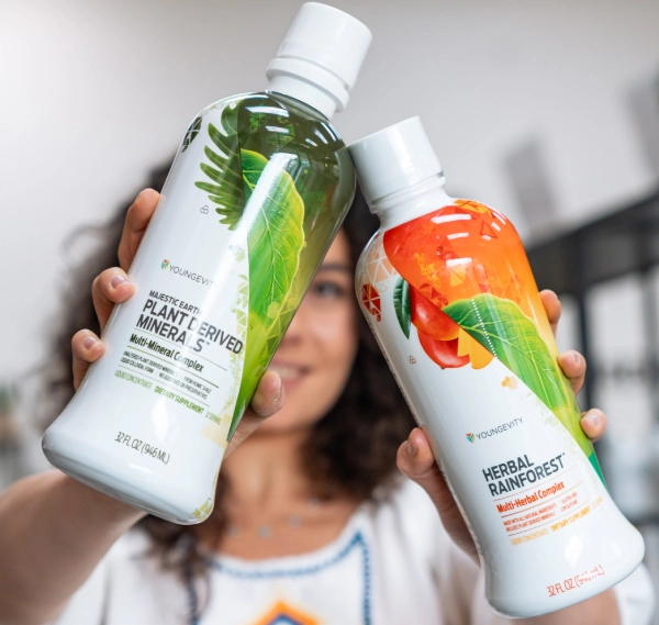 Woman holding two colorful lotion bottles with botanical designs.