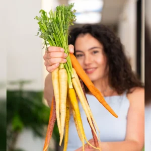 Woman holding a bunch of fresh yellow carrots.