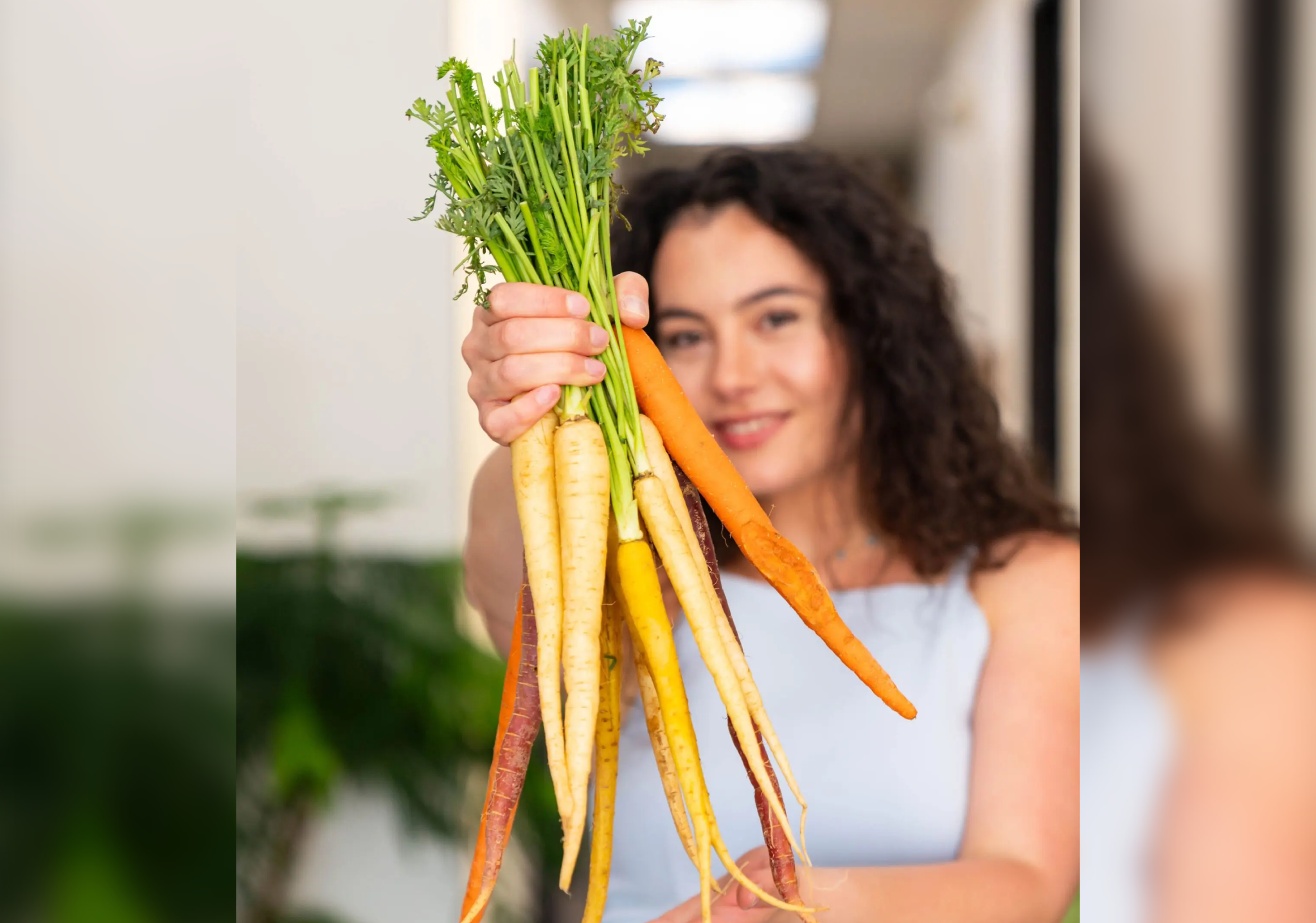 Woman holding a bunch of fresh yellow carrots.