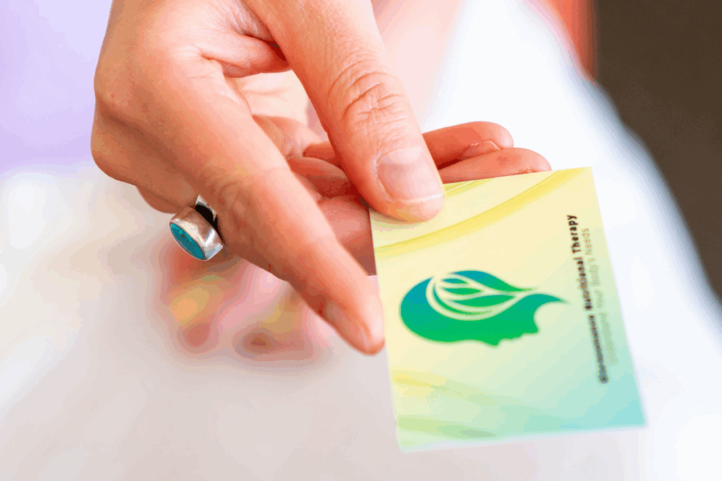Hand holding a green card with a leaf logo.
